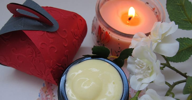 Skincare cream with bergamot essential oil and an orange candle
